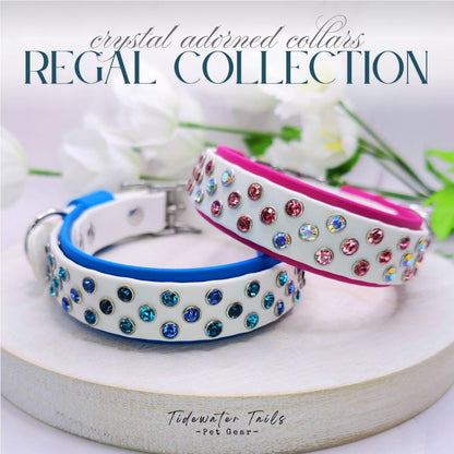 Two crystal-adorned dog collars on light surface with flowers in the background featuring the "Regal Collection'" design.